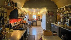 A compact kitchen with a gas stove, shelves with bottles, and a sign reading "GOOD MORNING COFFEE SHOP FRESH BREWED." - The Roadrunner: Experience Arizona Agritourism (Kingman)