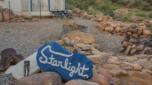 A rustic cabin with a porch, surrounded by rocks and a mountain backdrop. - The Roadrunner: Experience Arizona Agritourism (Kingman)