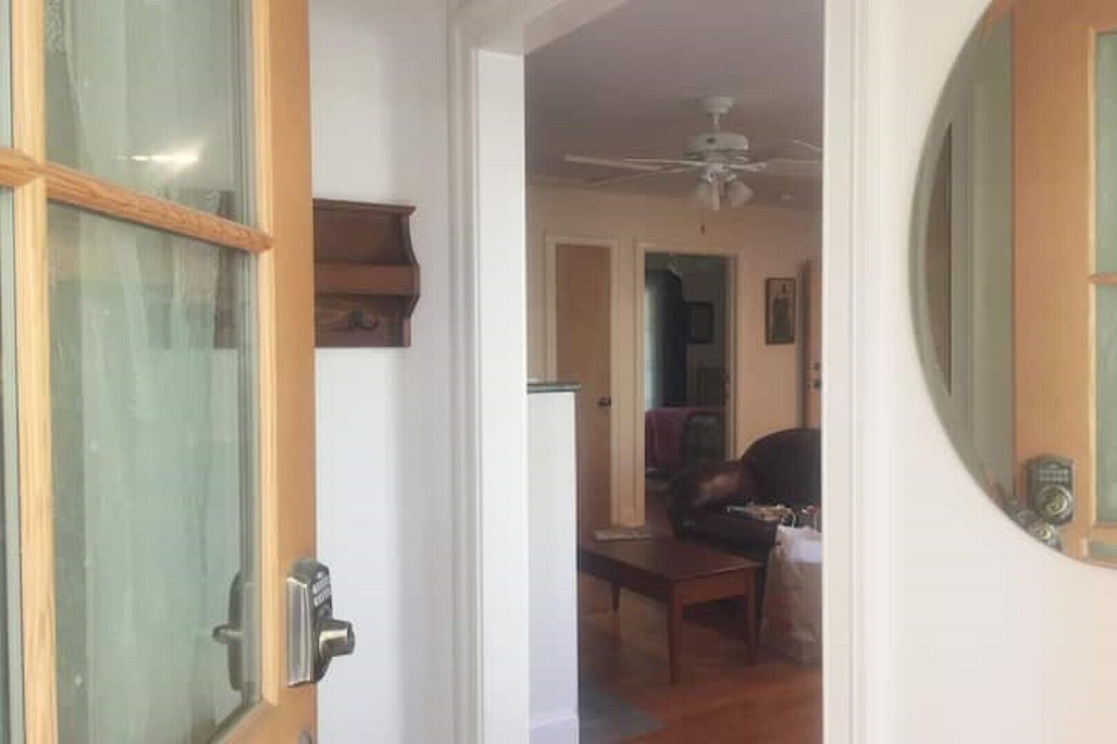 A doorway leading into a room with a ceiling fan, a wooden table, and a leather chair.