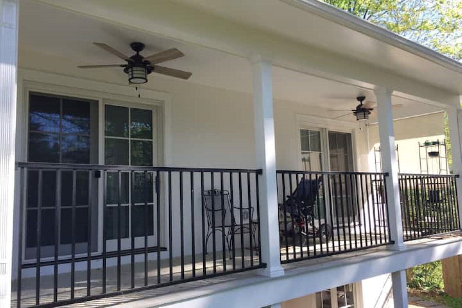 Une véranda couverte avec une balustrade, un ventilateur de plafond et une fenêtre.