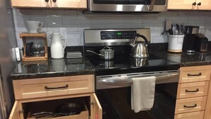 A modern kitchen with a stainless steel microwave, a digital clock, and a kettle on the stove. - Rugby Road Residential -RRR- near UVa and downtown (Charlottesville)