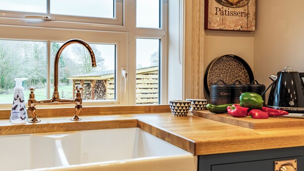 A kitchen with a large sink, a window with a view of a wooden structure outside, and a coffee maker on the counter. - 1 bedroom accommodation in Willoughby (Willoughby)