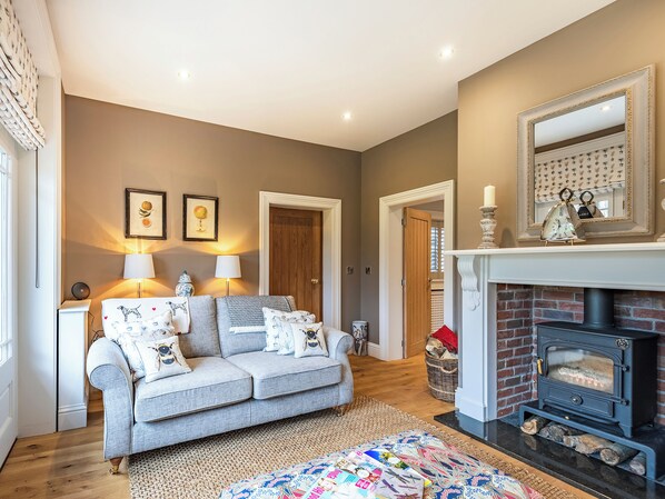 A cozy living room with a sofa, lamps, a fireplace, and a mirror.