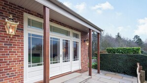 A brick house with a white door, a porch with stone steps, and a hedge in the background. - 1 bedroom accommodation in Willoughby (Willoughby)