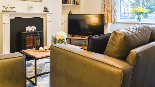 A living room with a fireplace, a television, a sofa, and a bookshelf. - A delightful haven for walkers and cyclists. (Skipton)