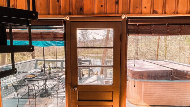 A wooden cabin with a glass door leading to an outdoor deck with a table and chairs. - Whispering Waters A-frame (Hocking Hills Area) (Rockbridge)
