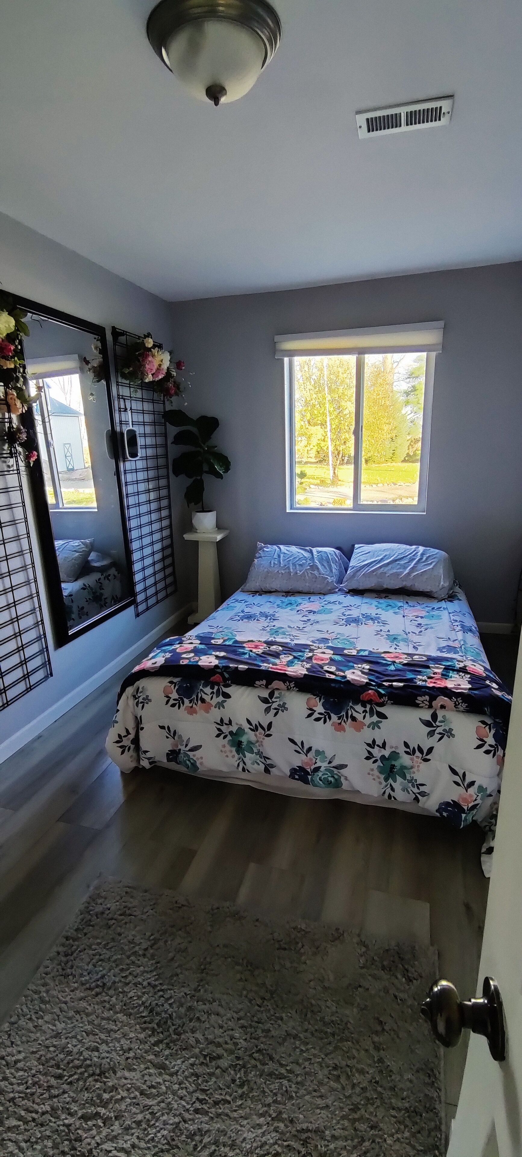 Ein Schlafzimmer mit Bett, Fenster, Tür und Deckenventilator.