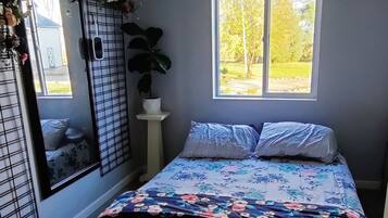 Ein Schlafzimmer mit Bett, Fenster, Tür und Deckenventilator.
