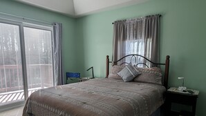 A bedroom with a bed, a nightstand, a chair, a ceiling fan, and a view of the outside through a sliding door. - 1400 Square feet of space, isolate in  three acres lot. (Sutherland)