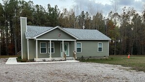 A single-story house with a sloped roof, a front porch, and a small front yard. - 1400 Square feet of space, isolate in  three acres lot. (Sutherland)