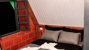 A room with a sloped ceiling, a bed with grey bedding, a ladder against the wall, and a hanging light fixture. - Pousada Recanto da Lua - Alto Caparaó (Alto Caparao)
