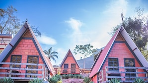 A row of red-roofed, triangular buildings with wooden balconies and windows, surrounded by greenery. - Pousada Recanto da Lua - Alto Caparaó (Alto Caparao)