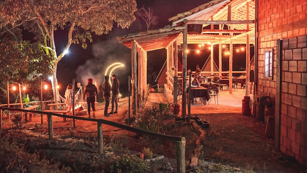 A rustic outdoor dining area with a covered seating area, a brick building, and a tree. - Pousada Recanto da Lua - Alto Caparaó (Alto Caparao)