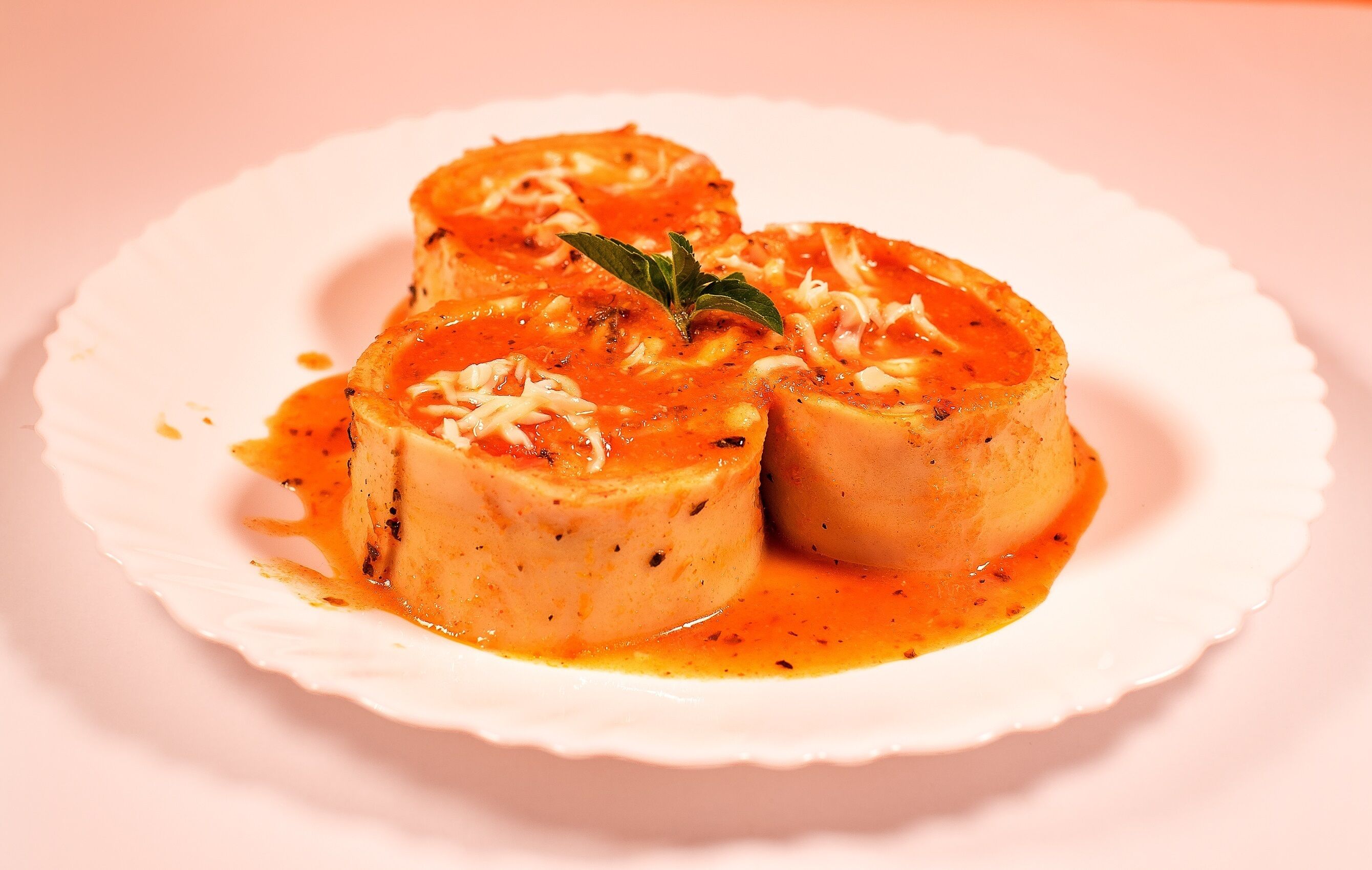 A plate of stuffed mushrooms with a tomato-based sauce and cheese garnish.