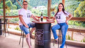 A couple seated at a round table with a beer barrel labeled 'Led Zeppelin' in a covered outdoor area with greenery in the background.
