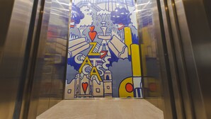 L’intérieur d’un ascenseur est décoré d’une fresque représentant un paysage urbain, avec des bâtiments et un pont.