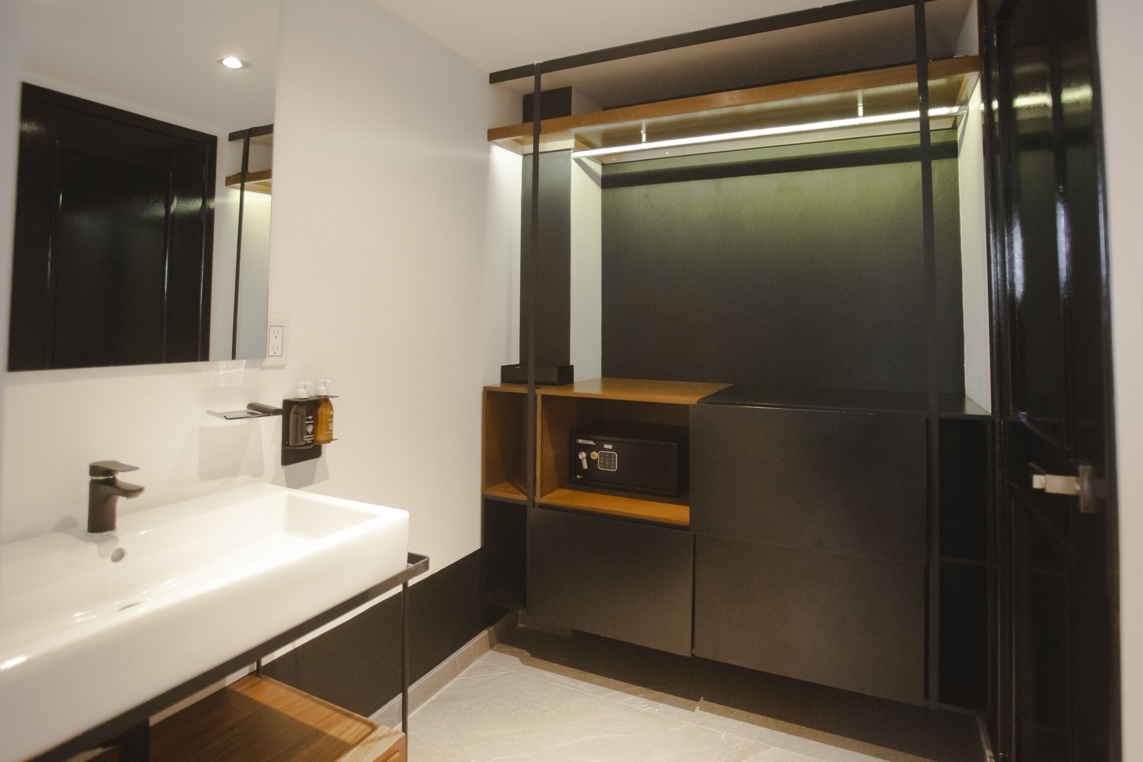 A modern bathroom with a white sink, a mirror, and a built-in cabinet with a wooden shelf.