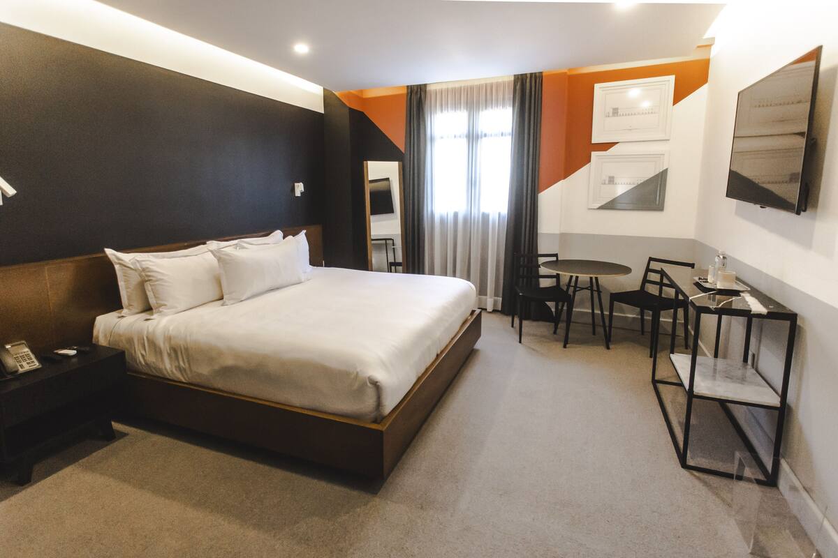 A hotel room with a large bed, a desk, and a chair.