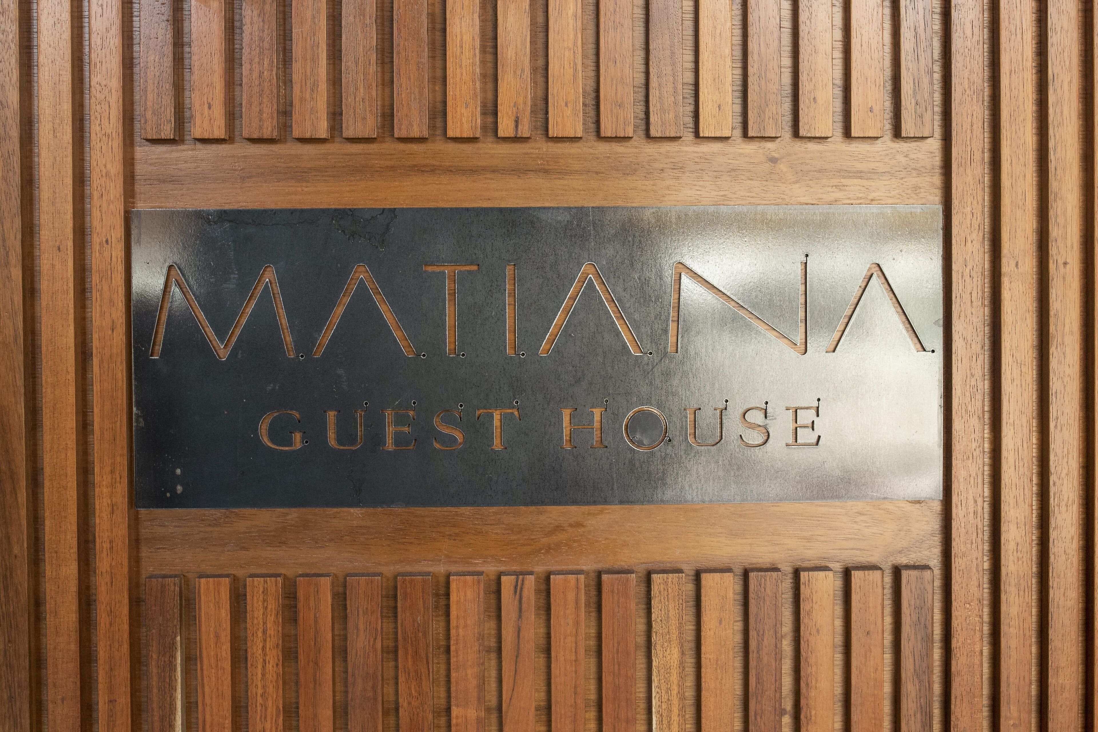 A sign with the text 'MATIANA GUEST HOUSE' on a wooden panel.