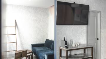 A room with a sofa, a coffee table, a TV mounted on the wall, and a door.