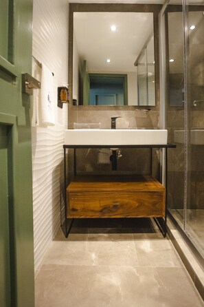 Een moderne badkamer met een wit wastafelmeubel, een houten kast en een douchecabine met glazen wanden.