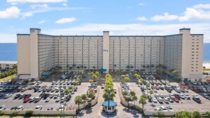 Een groot hotel met meerdere verdiepingen en een parkeerplaats ervoor.