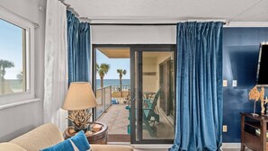 Een kamer met uitzicht op het strand, een bank, een lamp en een tafel met een decoratief object.