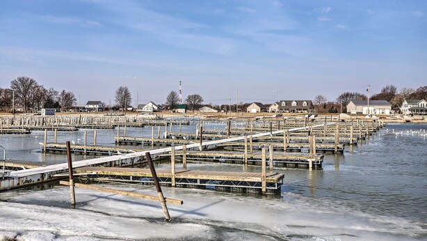 Une propriété située au bord de l’eau, dotée de plusieurs quais s’étendant sur une étendue d’eau gelée, et entourée d’immeubles résidentiels.