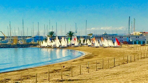 A beach with sailboats lined up along the shore, a sandy beach, and a clear blue sky. - Sea and Relax Portosole private apartment (Sanremo)