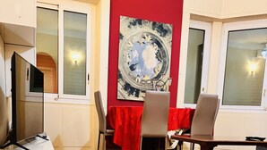 A room with a wooden parquet floor, a dining table with chairs, a red tablecloth, and a large abstract painting on the wall. - Sea and Relax Portosole private apartment (Sanremo)