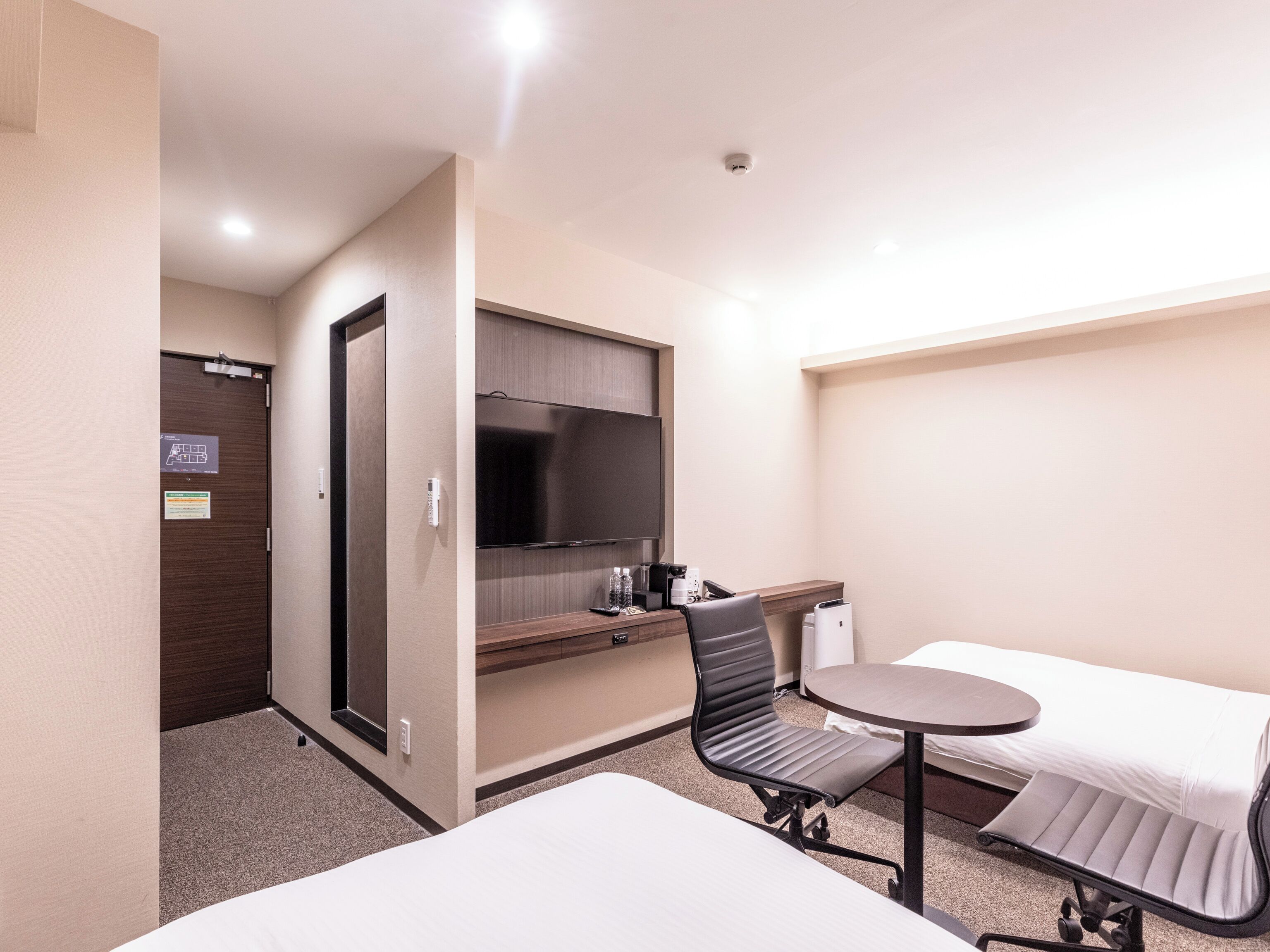 Une chambre d’hôtel comprenant un lit, un bureau avec une chaise, une télévision et une petite table.
