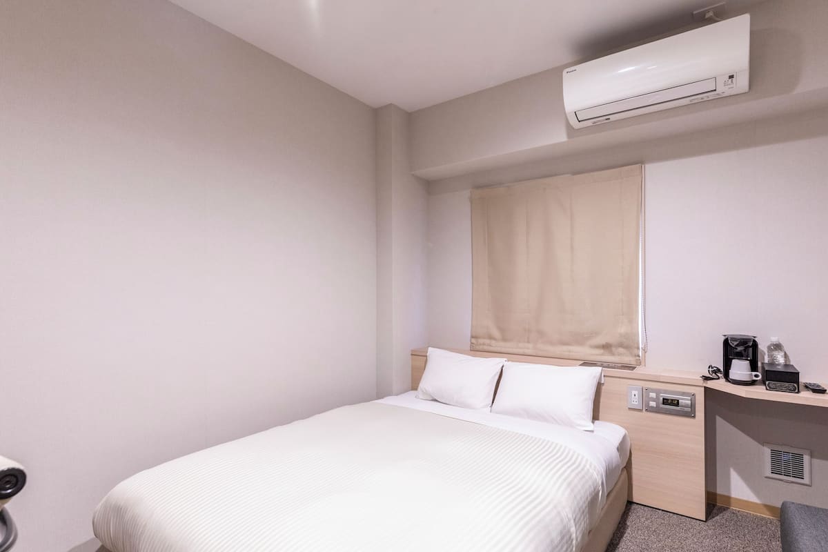 Habitación de hotel con cama, escritorio, cafetera y aire acondicionado.