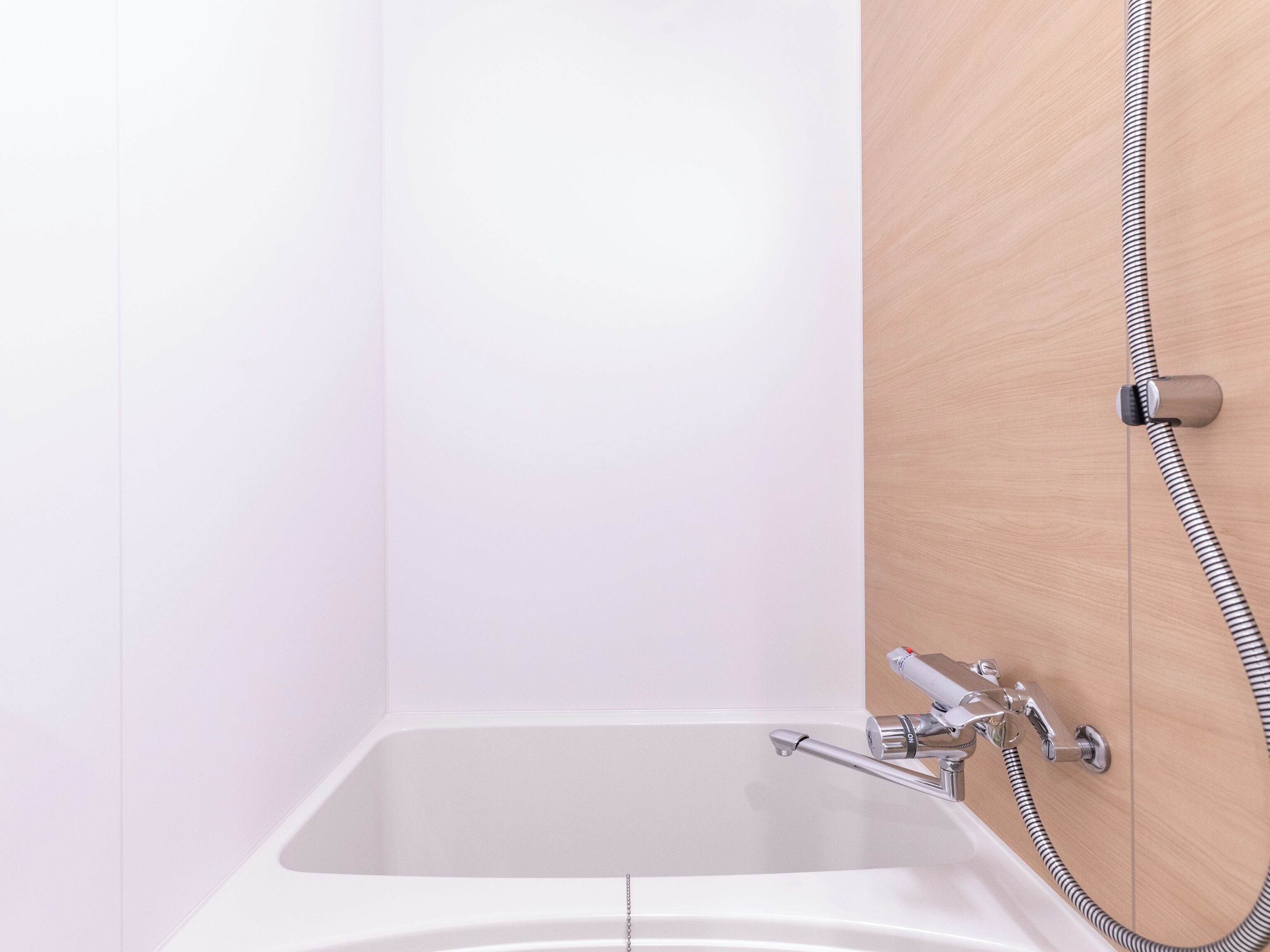 A modern bathroom with a white bathtub, chrome fixtures, and a wooden panel wall.