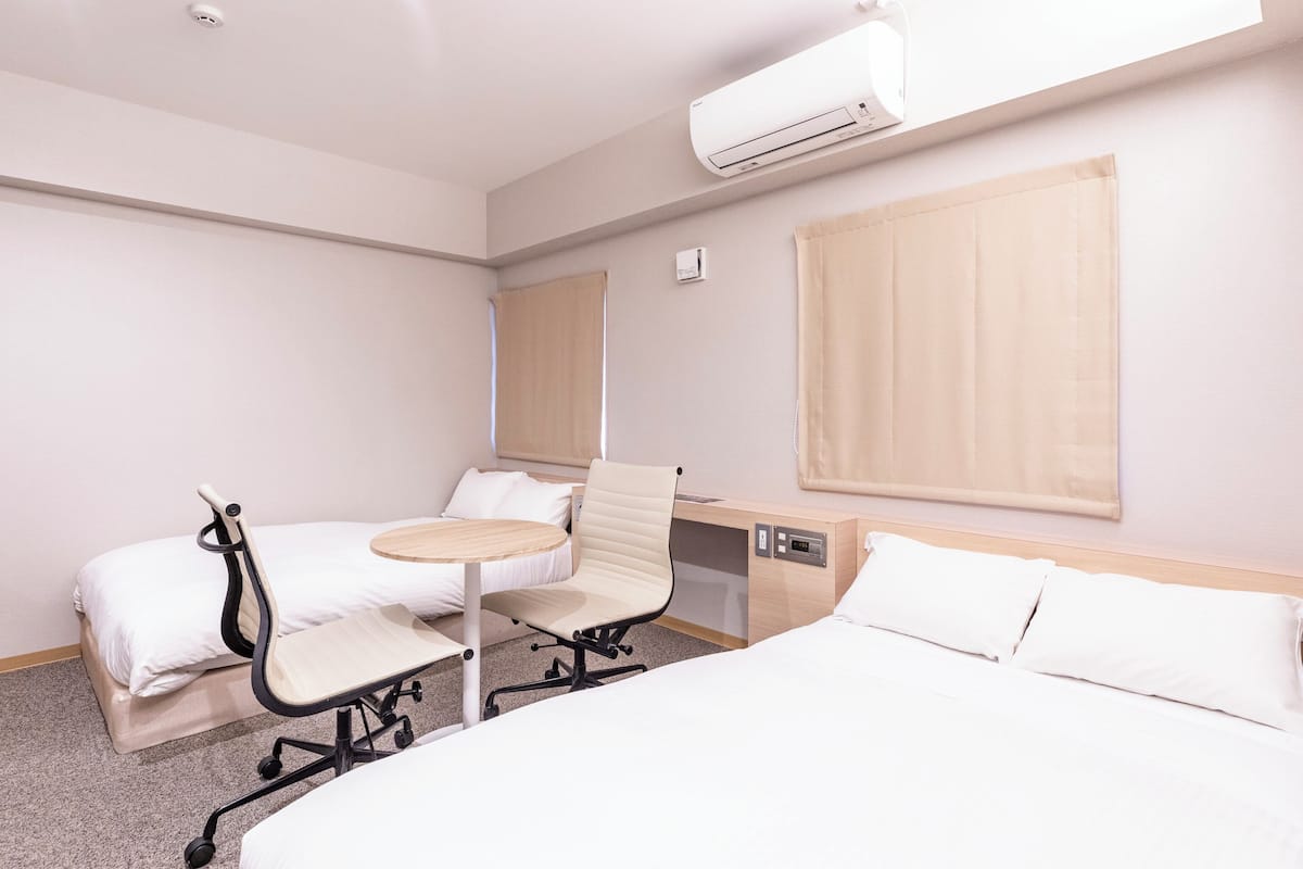 Habitación de hotel con cama, escritorio, silla, mesita y aire acondicionado.