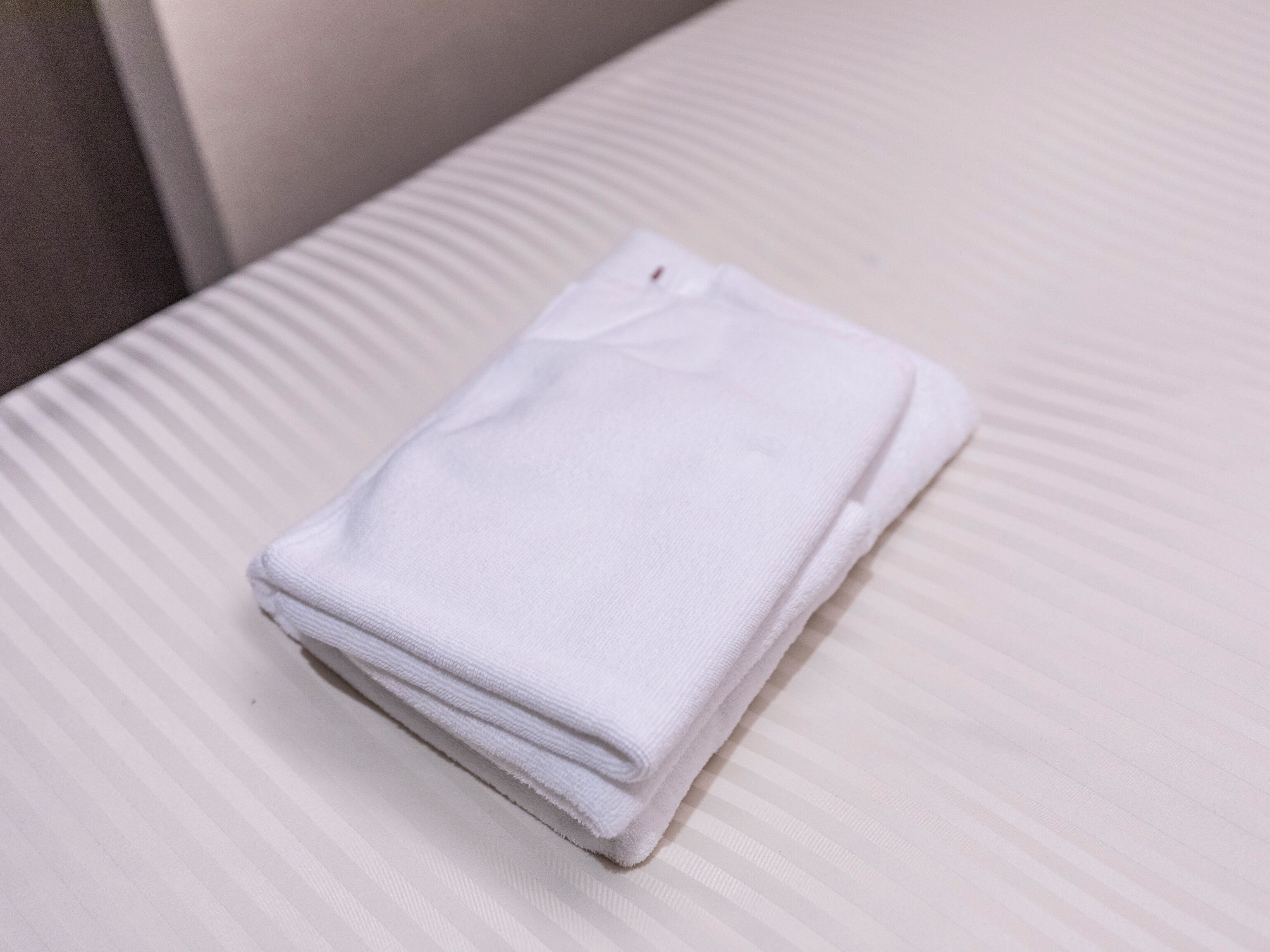 A neatly folded white towel on a striped surface.