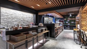 Un área de cocina moderna con listones de madera en el techo, una pared de piedra y diversos electrodomésticos.