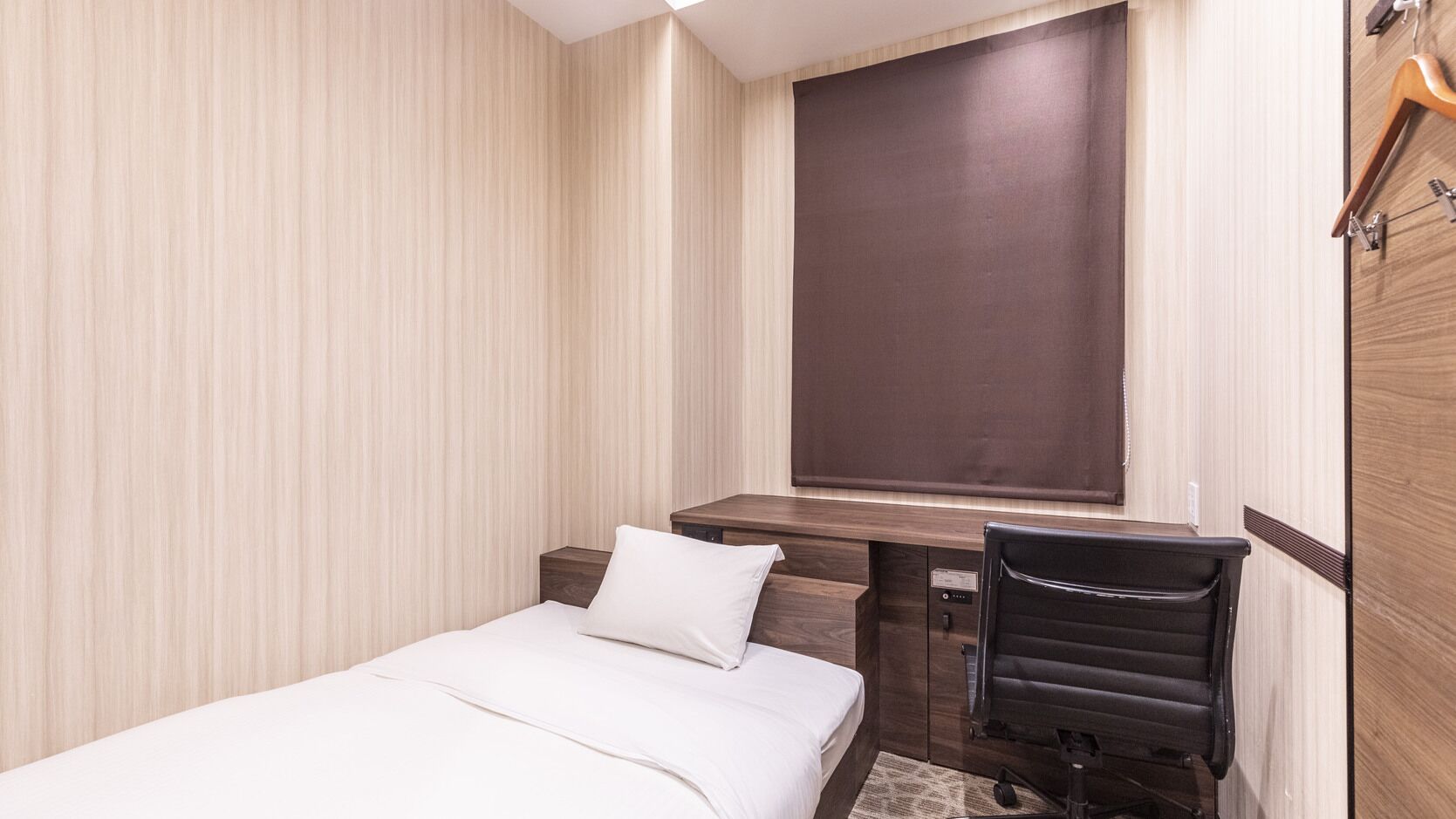Una habitació d'hotel amb un llit, un escriptori, una cadira i una finestra.