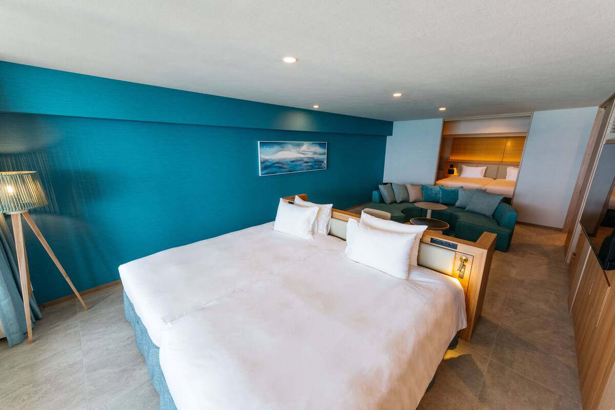 Quarto de hotel moderno com uma cama grande, um sofá e uma escrivaninha.
