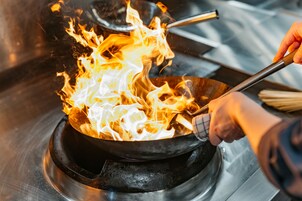 Una persona cocinando en una sartén sobre la hornilla.