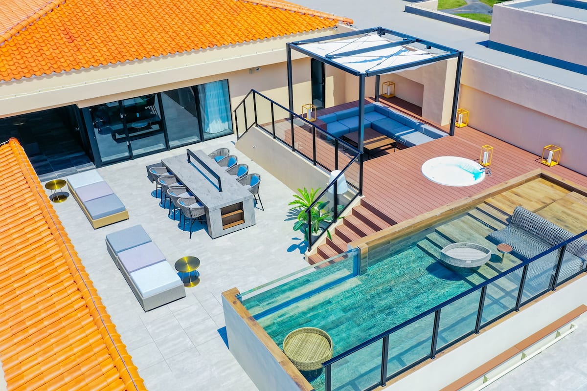 Uma área de piscina no terraço com estrutura de vidro, assentos e uma banheira de hidromassagem.