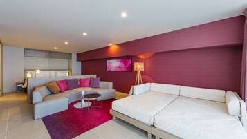 Una habitación de hotel moderna con un sofá, una cama, una mesita y una alfombra roja.