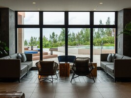 Amplia sala de estar con grandes ventanales, piscina y mobiliario exterior.