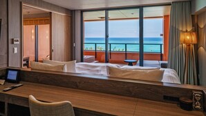 Une chambre d’hôtel avec un grand balcon, un lit, un bureau et un ordinateur portable.