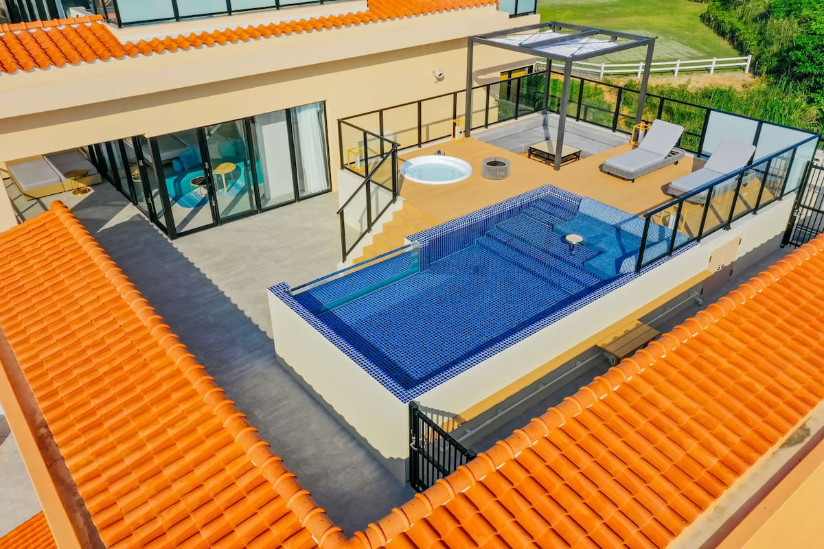 Piscina no terraço com guarda-corpos de vidro, uma banheira de hidromassagem e espreguiçadeiras.