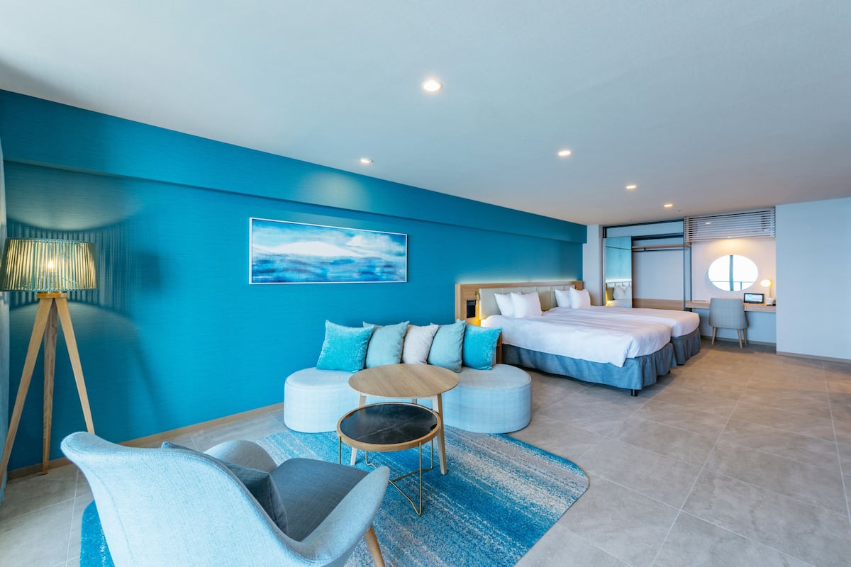 Quarto de hotel moderno com uma cama grande, um sofá, uma pequena mesa e uma escrivaninha.