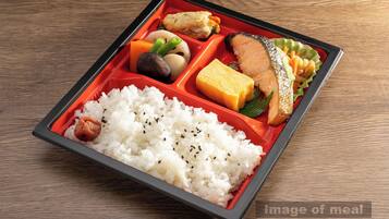 A bento box with rice, fish, tofu, and vegetables on a wooden table.