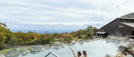 A hot spring area with clear water, large rocks, and a wooden building.