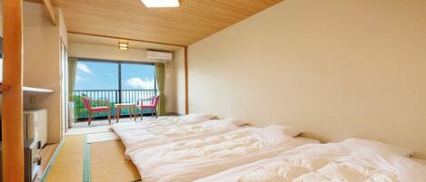 A hotel room with two beds, a balcony with chairs, and a view of the sky.