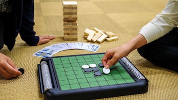 Un jeu de Go, avec un plateau à carreaux verts, des pierres noires et blanches, et des blocs de bois, le tout disposé sur un tapis tissé.