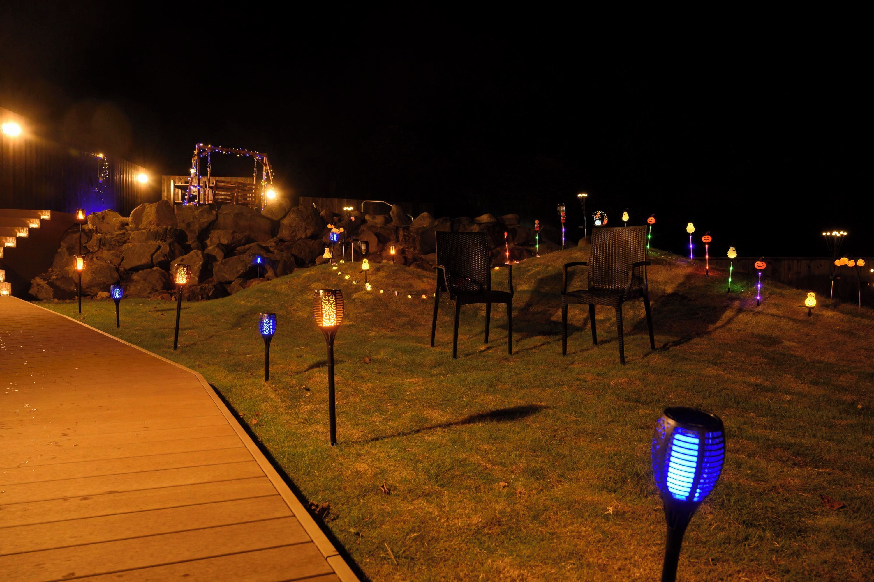 A nighttime outdoor area with a wooden deck, seating, and decorative lights.